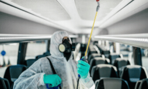 addetto alla sanificazione del pullman con tuta guanti e e maschera igenizza l'interno di un pullman